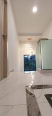 Modern hallway with marble flooring leading to a bright room with a view of the outdoors