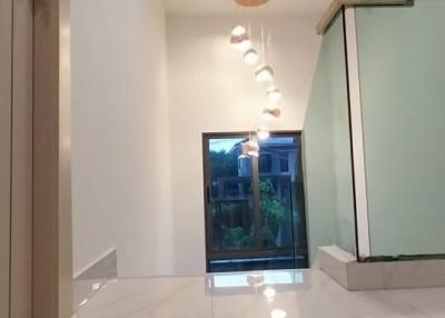 Modern hallway with marble flooring leading to a bright room with a view of the outdoors