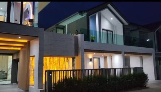 Modern two-story house exterior at dusk with illuminated interiors and stylish facade