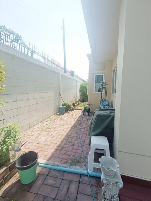 paved side yard with gardening equipment and high wall