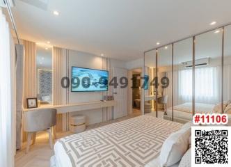 Modern bedroom with a large bed, mirrored wardrobe, desk area, and mounted TV