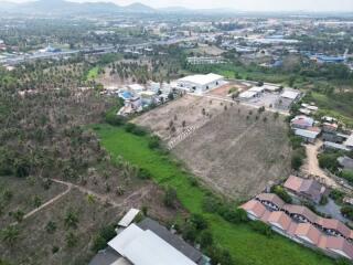 Aerial view of a spacious land plot near residential area with mountain backdrop