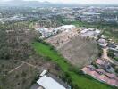 Aerial view of a spacious land plot near residential area with mountain backdrop