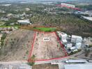 Aerial view of a vacant land lot for sale, bordered in red, with surrounding infrastructure