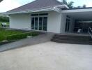 Exterior view of a modern single-story house with an open garage and steps leading to the entrance