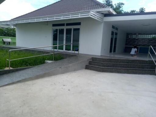 Exterior view of a modern single-story house with an open garage and steps leading to the entrance