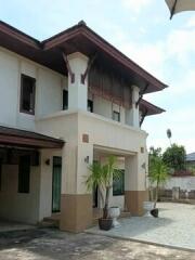 Two-story house facade with a porch and plants