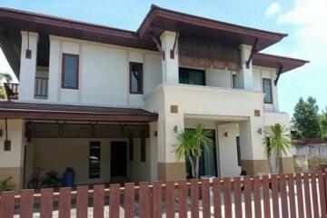 Two-storey residential house with balcony and tropical landscaping