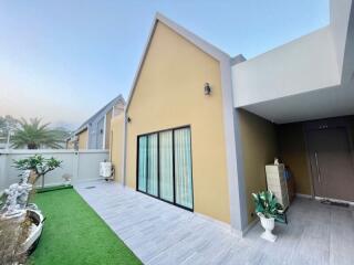 Modern house exterior with sliding glass doors, artificial lawn, and a covered entrance