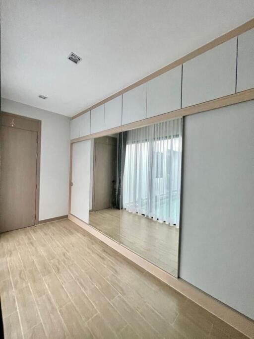 Spacious bedroom with large mirrored wardrobe and wooden flooring