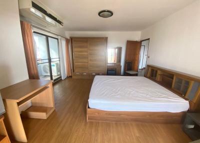Spacious bedroom with wooden furniture and balcony access
