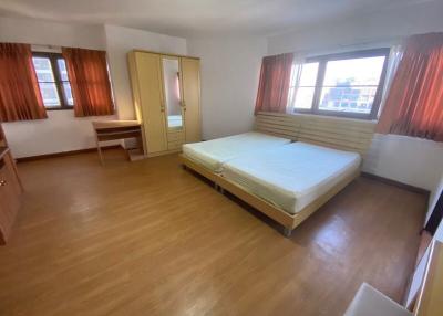 Spacious bedroom with large bed, hardwood flooring, and ample natural light