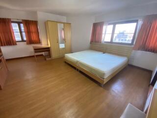 Spacious bedroom with large bed, hardwood flooring, and ample natural light