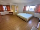 Spacious bedroom with large bed, hardwood flooring, and ample natural light