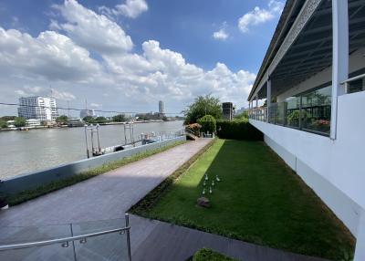 Spacious riverfront outdoor area with green lawn and city skyline