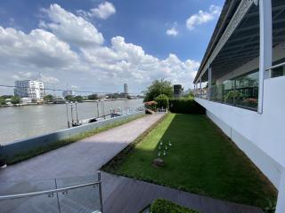 Spacious riverfront outdoor area with green lawn and city skyline