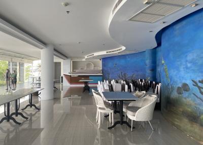 Spacious combined dining and kitchen area with modern furniture and ocean-themed mural
