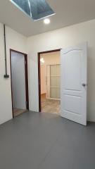 Interior view of a room with tiled flooring, white doors, and a skylight