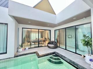 Modern living area with pool, skylights, and view into dining room