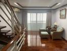 Cozy living room with wooden floors, staircase, and ample natural light