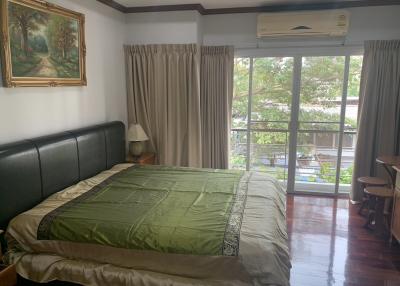 Spacious bedroom with large bed, hardwood floors and garden view