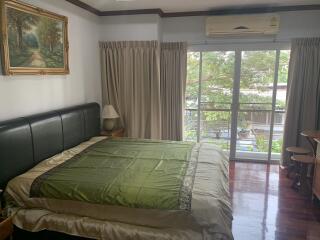 Spacious bedroom with large bed, hardwood floors and garden view