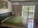 Spacious bedroom with large bed, hardwood floors and garden view