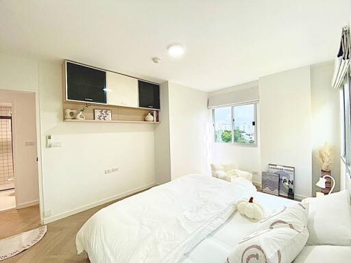 Modern bedroom with white bedding and wall-mounted TV