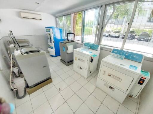 Spacious communal laundry room with multiple appliances and bright window