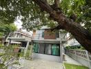 Spacious two-story house with large tree in the front yard and balcony