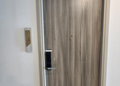 Modern wooden door entrance with digital lock and white walls