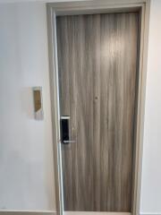 Modern wooden door entrance with digital lock and white walls