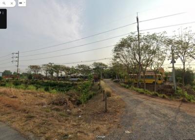 Empty land available for development with surrounding greenery and a clear sky