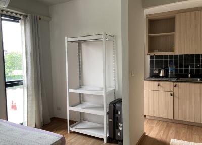 Cozy bedroom with open wardrobe and adjacent kitchenette