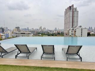 Infinity pool with city skyline and lounge chairs at an apartment complex