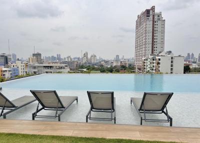 Infinity pool with city skyline and lounge chairs at an apartment complex