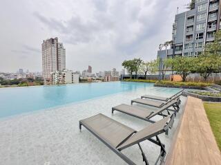 Outdoor swimming pool with city skyline view and lounging chairs