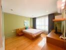 Bright and spacious bedroom with a large bed and hardwood floors