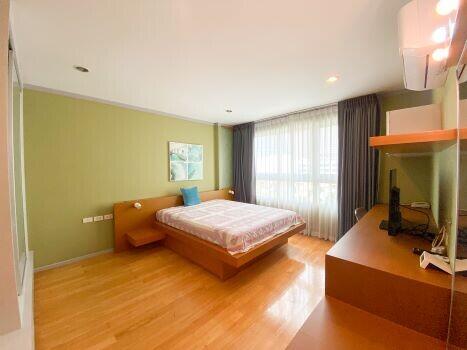 Bright and spacious bedroom with a large bed and hardwood floors