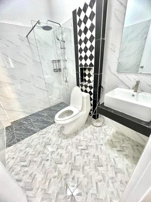 Modern bathroom with chevron flooring, black and white tiles, and glass shower