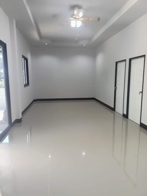 Spacious and well-lit empty room with glossy tiled flooring