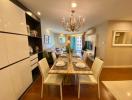 Elegant dining room with chandelier over a wooden table set, adjacent to an open living area