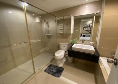 Modern bathroom interior with glass shower enclosure, beige tiles, and contemporary fixtures