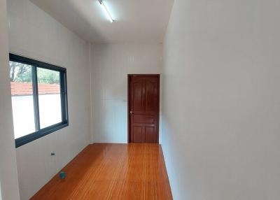 Compact bedroom with wooden flooring and a window