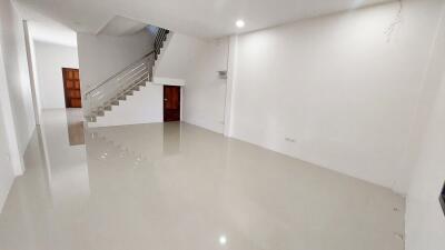 Spacious living area with glossy tiled flooring and an elegant staircase