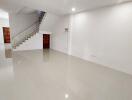 Spacious living area with glossy tiled flooring and an elegant staircase