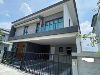 Modern two-story house with spacious garage and balcony under a clear blue sky