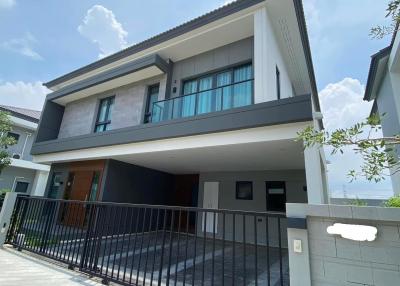 Modern two-story house with spacious garage and balcony under a clear blue sky