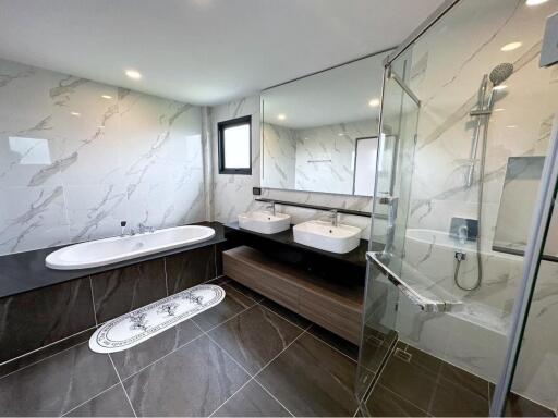 Modern bathroom interior with dual sinks, bathtub, and a glass shower