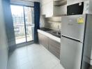 Modern compact kitchen with stainless steel appliances and balcony access